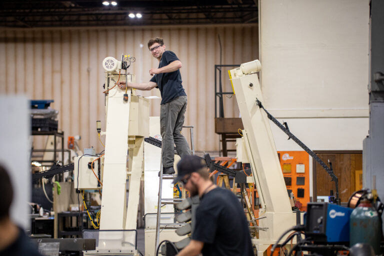 Man up on a latter working on a machine